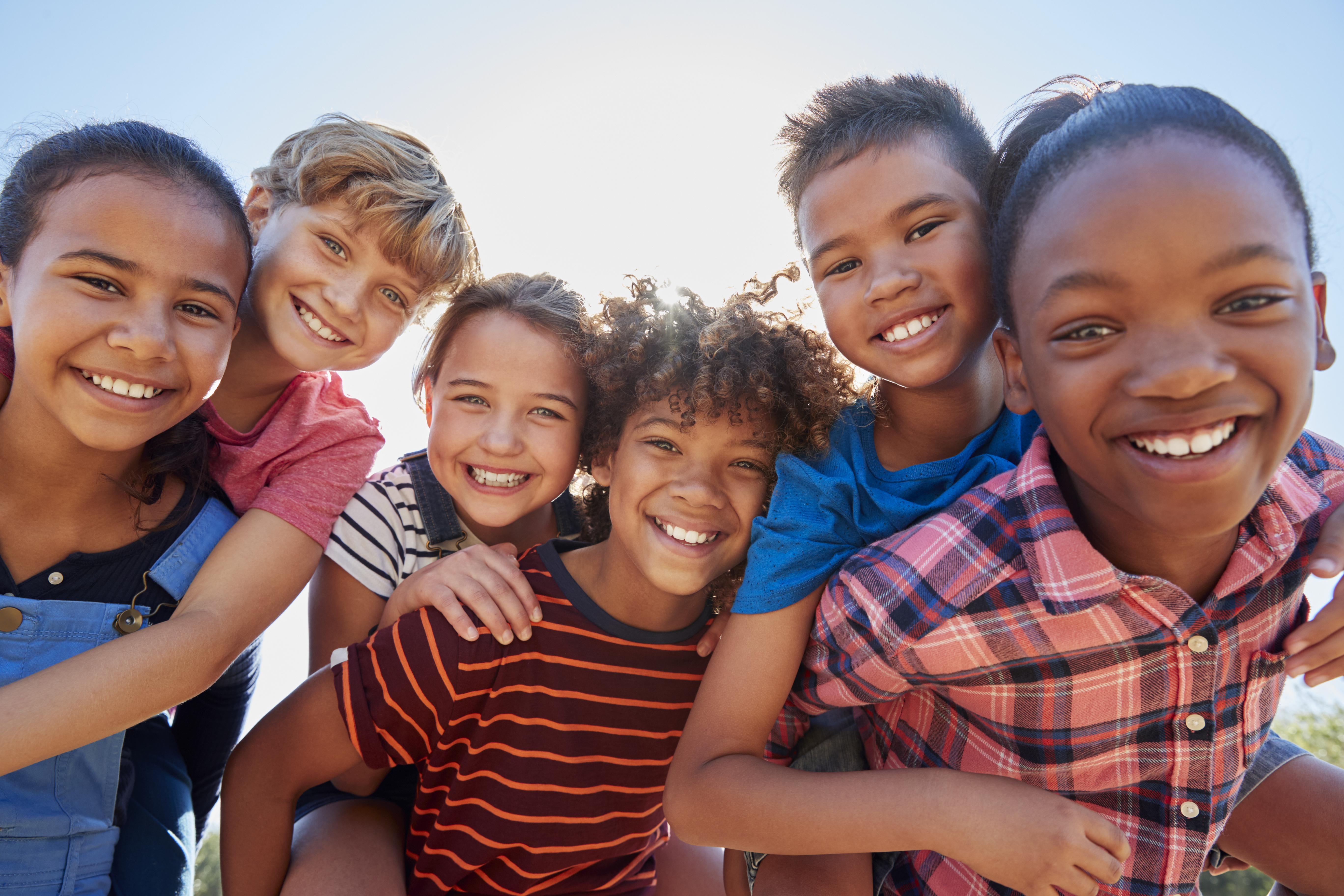 Six preteen friends piggybacking in park